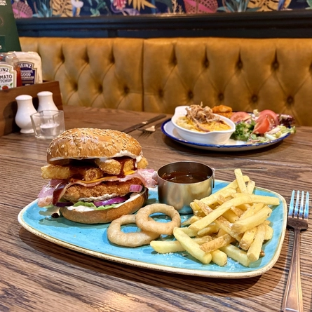 Plated dishes for Burger of the Month October served at Greene King Pubs.  One is a roasting dish of Macaroni Cheese and a plated chicken burger.