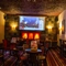 Interior dining area of a pub with a fireplace and a TV.