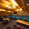 The interior restaurant seating area at the Old School House in Aberdeen, with a long, upholstered booth seat along one side of the room, a TV on the wall above it, and a wooden staircase leading to the upper floor.