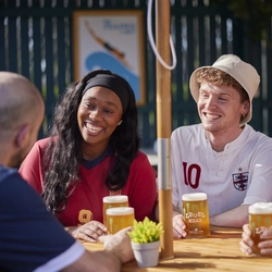 A mixed group of people seated at an outdoor table holding drinks.