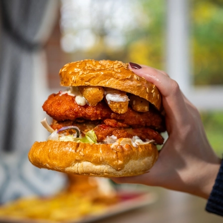 A customer holding a Tingly Tedster burger available at Hungry Horse venues.