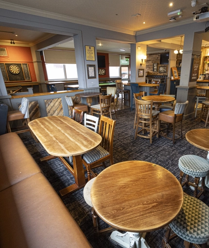 Interior dining area of a pub with a TV, a bar and a gambling machine.