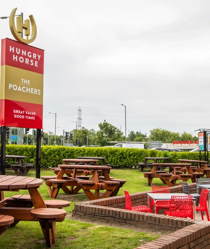 The exterior beer garden and seating area with pub signage at the Poachers.