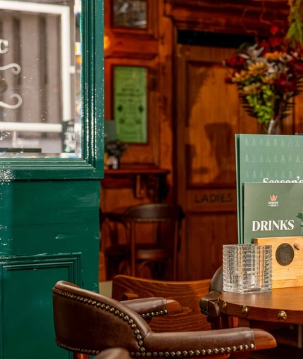 A close up view of a restaurant table laden with food and drinks menus, a tealight, and a table decoration, in the bar area of Adam & Eve.