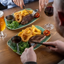 People sitting eating steak and chips.