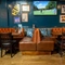 The interior restaurant seating area of the Cock & Pye, with upholstered booth seating and a TV on the wall.