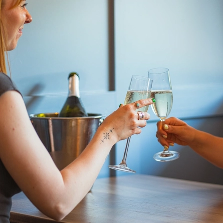 Two women sat at an indoor table, enjoying a glass of sparkling wine.