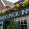 A close up view of the words "The Woolpack Inn" in white lettering on a dark green background, on the exterior wall of The Woolpack Inn in Norwich.