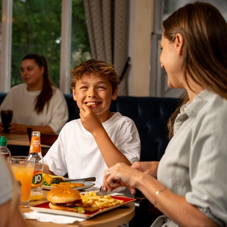 A parent and child sitting at an indoor table, enjoying a meal.