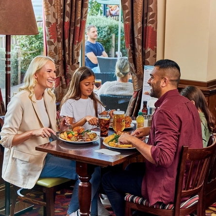 family sitting round a table in a restaurant eating a roast dinner