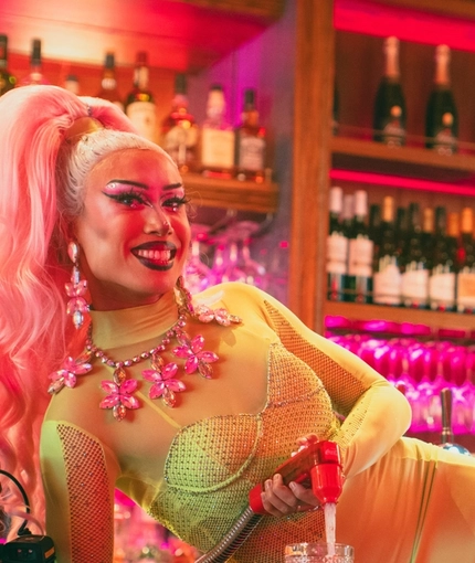 An image of one of the Drag Queens lay across the interior bar preparing a drink at The City Of Quebec.