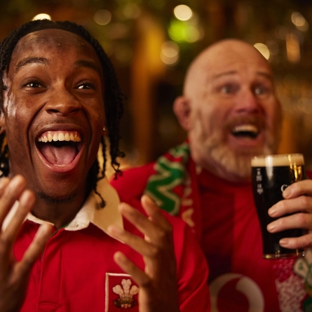 An image of a man wearing a sport team shirt, watching a sporting event.