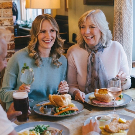 An image focusing on 2 family members sat within a group enjoying Mothers Day main dishes and drinks within the interior restaurant seating area at a Pub & Grill venue.