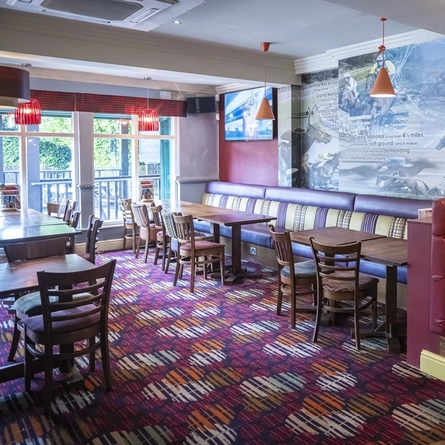 The interior restaurant seating area at the Blue Anchor in Aintree; with upholstered booth seating, and a TV on the wall.
