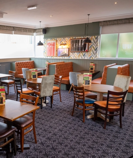 The interior restaurant seating area at the Devonshire Arms in Sheffield, with booth seating, a fireplace, and a TV on the wall above it.