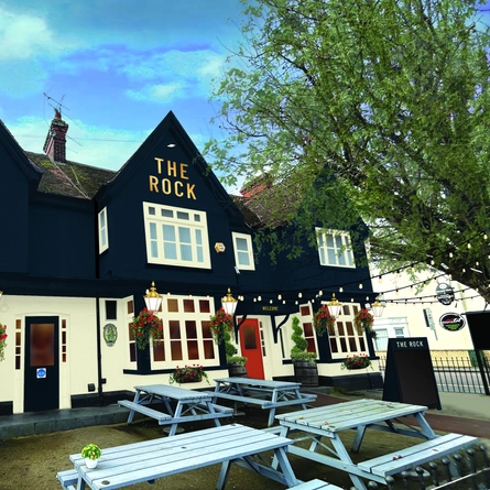The exterior facade with wooden outdoor seating at The Rock.
