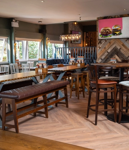 The interior restaurant seating area at The Man On The Moon, with upholstered seating, wooden tables, and TVs on the walls.
