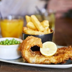 A plate of fish and chips, on an indoor table.