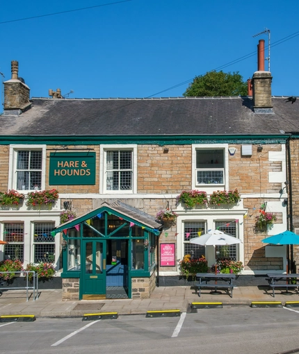The exterior facade and beer garden seating area at The Hare & Hounds.