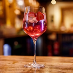 A cocktail in a stemmed Gin style glass on a bar.