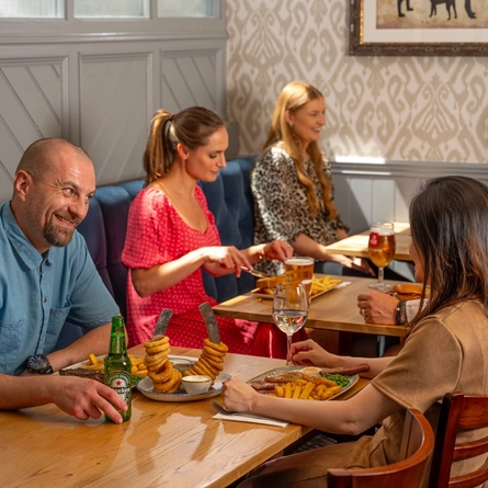 An image of a group of people enjoying various mains dishes and drinks within the interior restaurant seating area at a Hungry Horse venue.