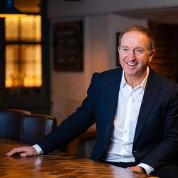 Nick Mackenzie seated at a table, smiling.