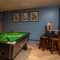 The interior games area at The Heron in Havant; with a pool table, a TV on the exposed brick wall, and a restaurant table with bar stool seating.