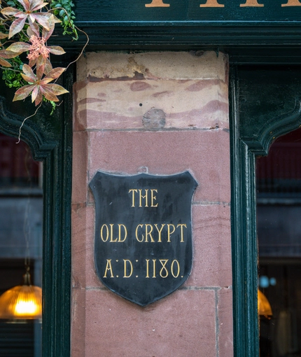 A close up image of an exterior historical information plaque with the wording "The Old Crypt AD 1180" at The Watergates Bar.