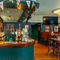 A close up view of the bar and interior restaurant seating area at the Royal George; with golden drinks trays on the counter, and a TV on the wall.