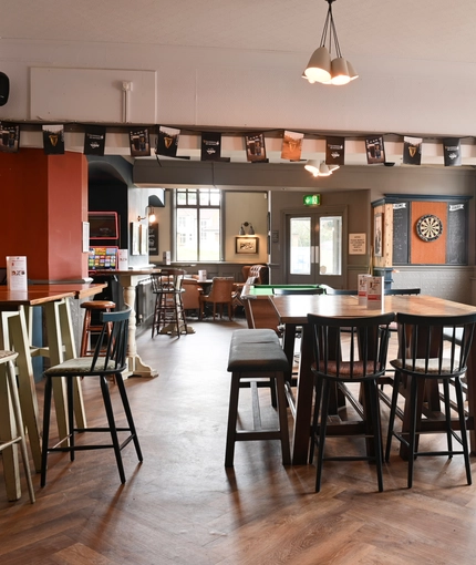 Interior dining area of a pub with a dartboard and a gambling machine.