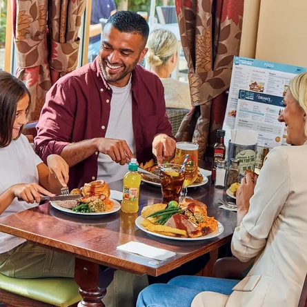 family sitting round a table in a restaurant eating a roast dinner