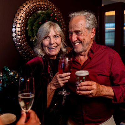 An image focusing on a 2 people stood within a group enjoying New Years Even drinks within the interior of a Community Social venue.