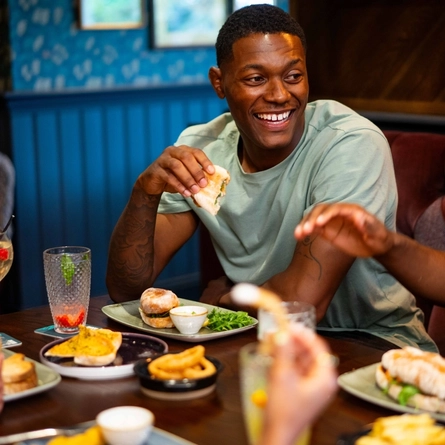 An image of various food and drinks being enjoyed within the interior restaurant seating area at a Community Pubs With Food venue.