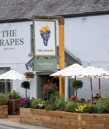 The outside of the Grapes, with some beer garden tables in front of it.