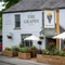 The outside of the Grapes, with some beer garden tables in front of it.