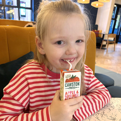 A young girl sat in the seating area drinking a Cawston Press carton at HighTales.