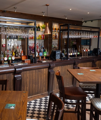 The bar and interior seating area at The Man On The Moon, with wooden tables and chairs.
