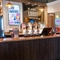 The bar inside The Lodge in Alvaston, with TVs on the wall, and bottles of wine and alcoholic spirits on wooden shelves behind the counter.