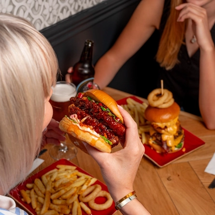 An image of 2 people enjoying burgers and drinks within the interior restaurant and seating area at a Hungry Horse venue.
