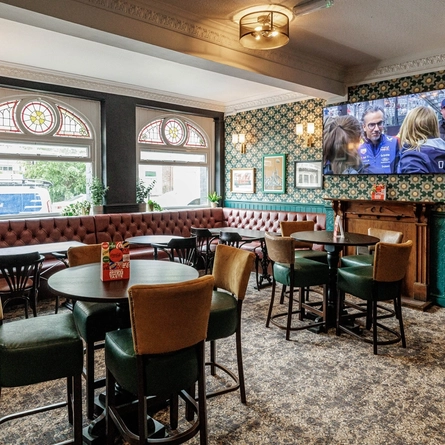 The interior restaurant seating area with tables, chairs, fireplace and wall mounted TV at The Clive Arms.