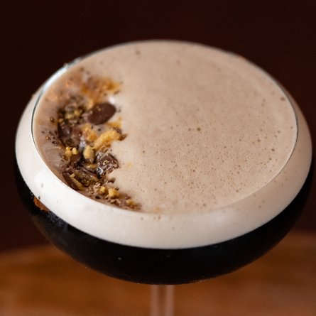 a cocktail sitting on a wooden table of a pub