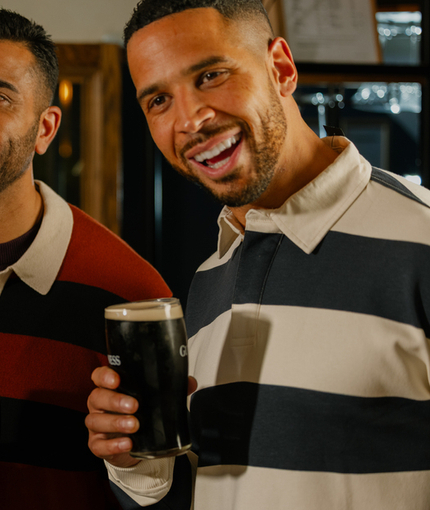 An image of 3 friends with pints of Guinness stood within the interior watching the Six Nations at The Crown.