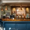 A close up view of the bar inside The Horsforth, with bottles of alcohol on wooden shelves behind the counter.