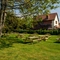 The exterior beer garden seating area at The Walkford in Walkford, with wooden picnic tables and trees on a large lawn.