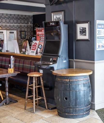 Interior dining area of a pub with a TV and a gambling machine.