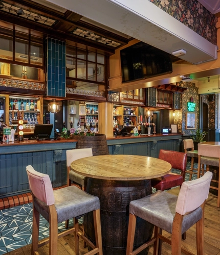 Interior dining area of a pub with a bar and a few TVs.