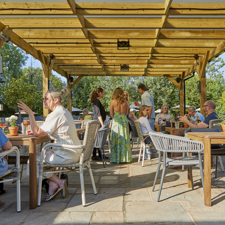 An image of people sat within the exterior partially covered beer garden seating area with various drinks at The Drum & Monkey.
