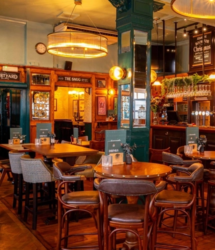 The wood panelled bar and interior restaurant seating area at Adam & Eve in St James, with a TV on the wall.