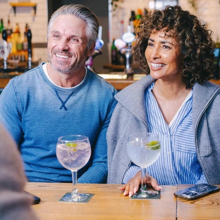 A group of friends sat in the interior seating area of a Greene King pub enjoying glasses of Gin at the Gin weekend takeover event. 