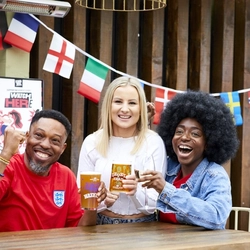A mixed group of people, sitting at an outdoor table reacting to sport event.